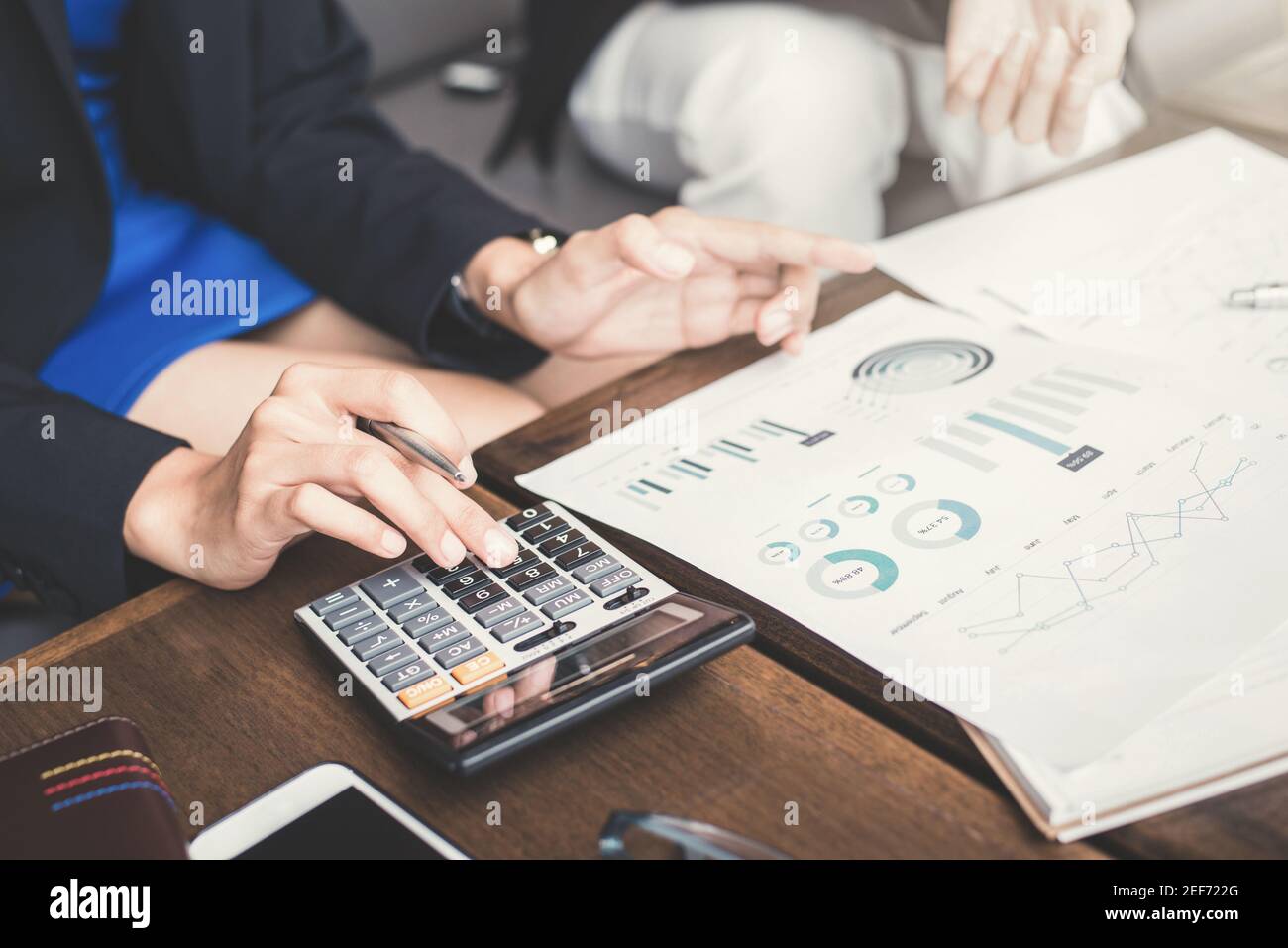 Donna d'affari che calcola e discute di documenti finanziari - valutazione e valutazione concetti Foto Stock