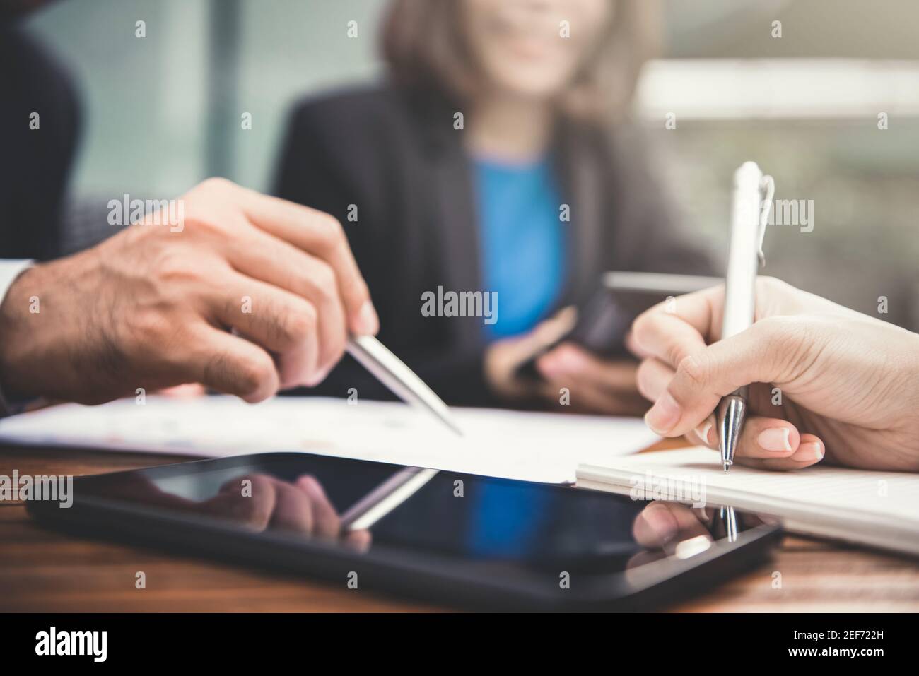 Uomini d'affari che scrivono e discutono documenti con il computer tablet su il tavolo Foto Stock Uomini d'affari che scrivono e discutono documenti con il computer tablet su il tavolo Foto Stock