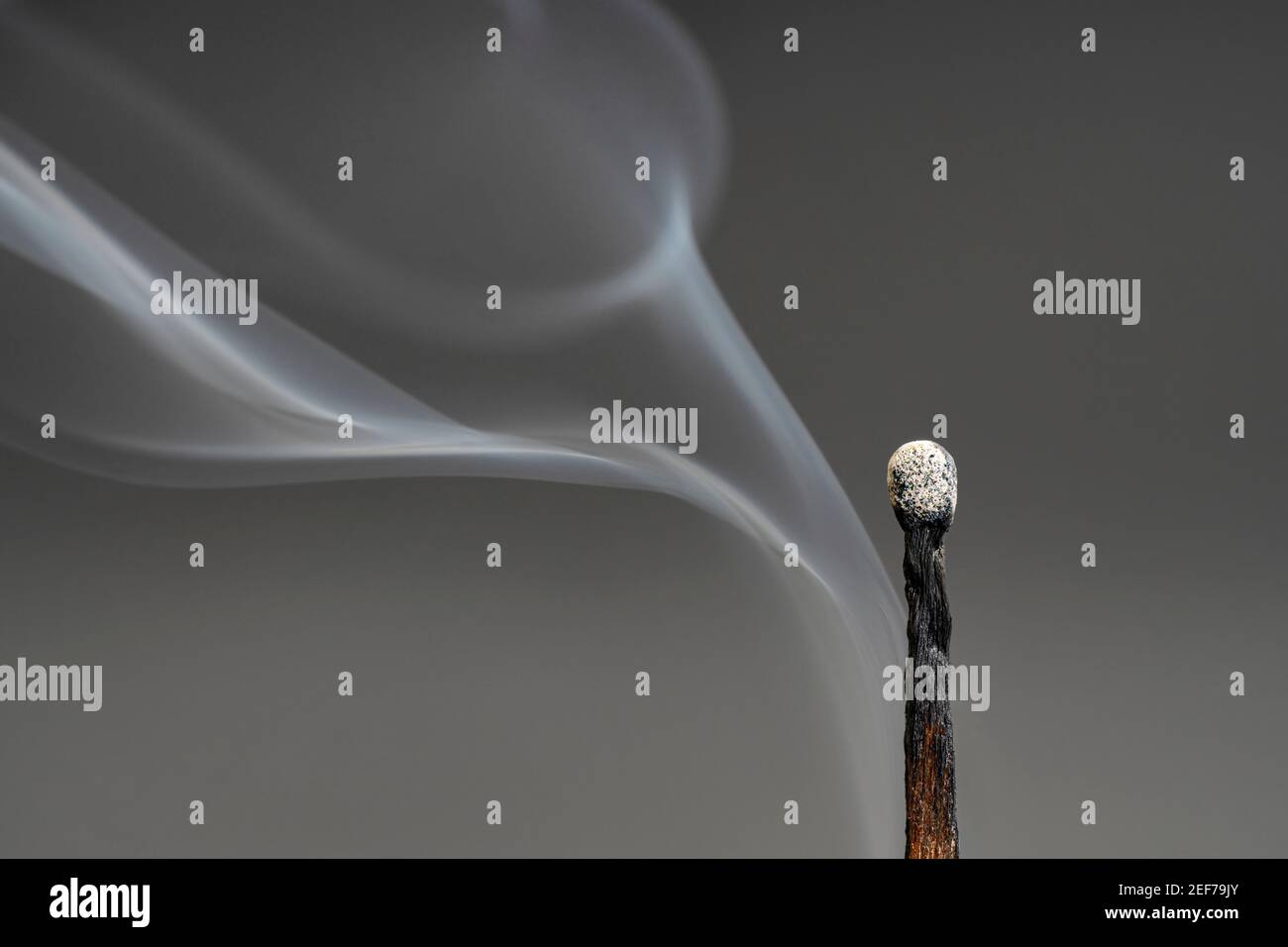 Primo piano del fumo proveniente da una partita estinta uno sfondo grigio Foto Stock