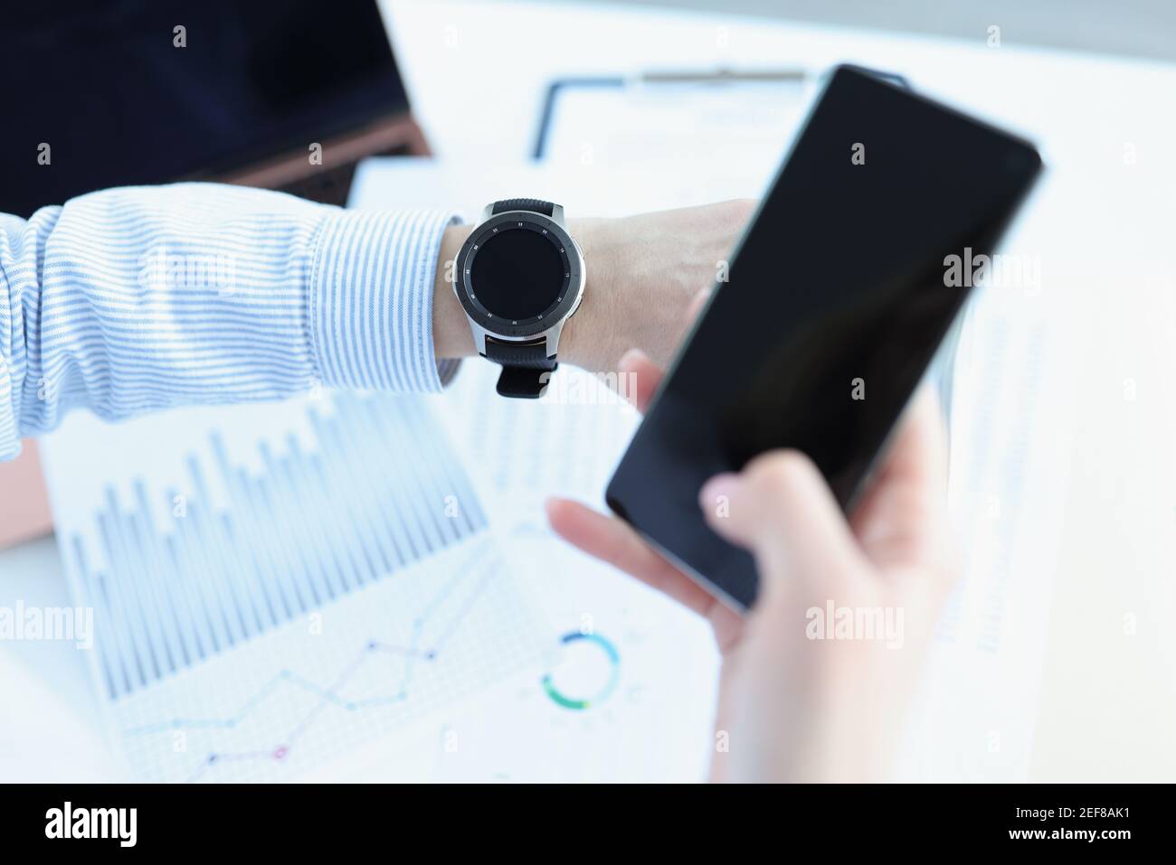 L'uomo tiene lo smartphone in mano e guarda in modo intelligente guarda Foto Stock