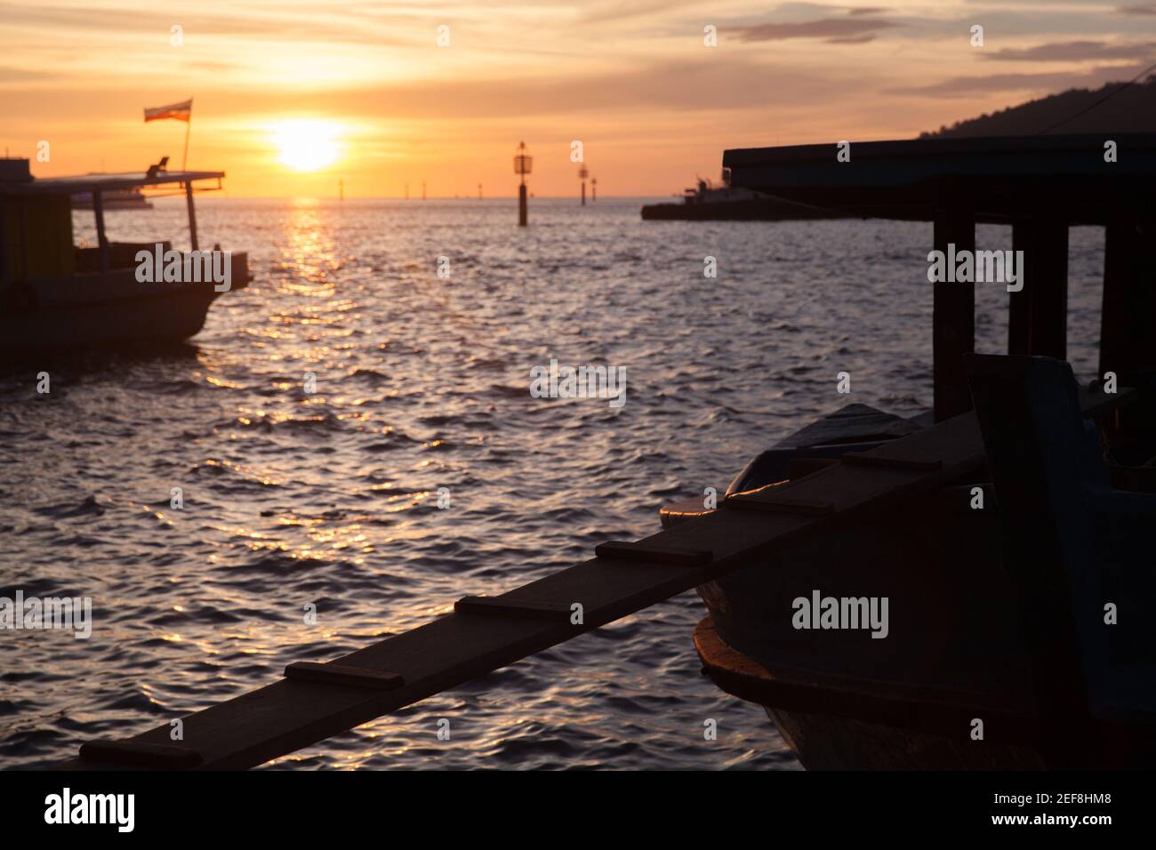 Silhouette di barche da pesca ormeggiate vicino KK Fish Market at tramonto Foto Stock