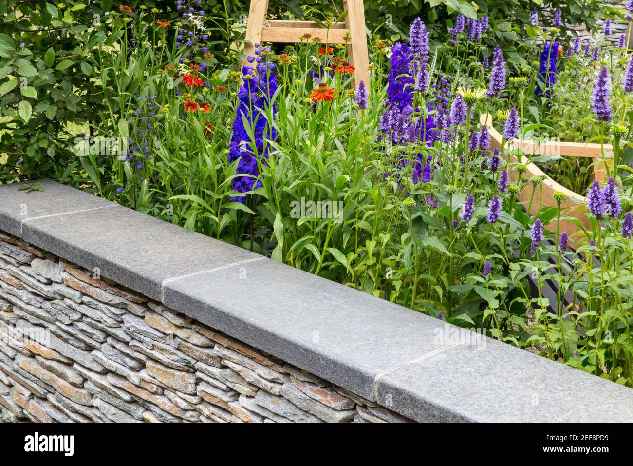 Un cottage inglese giardino di campagna con muro di pietra a secco e. Fiore letto giardino bordo di fiori Agastache in estate Londra Regno Unito, Inghilterra Foto Stock