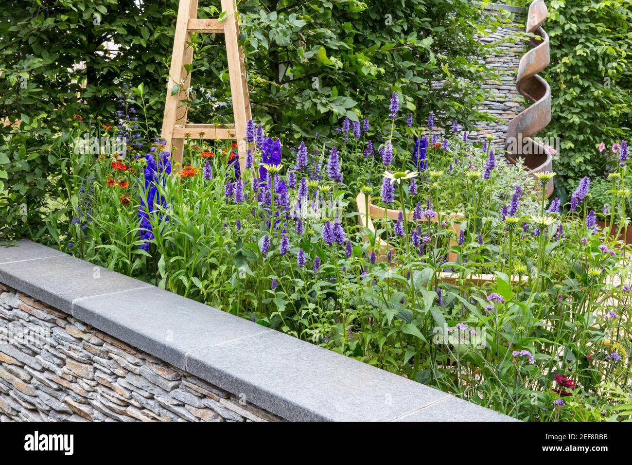 Cottage inglese giardino di campagna con vista su muro di pietra a secco e fiore letto giardino confine crescente Agastache fiori in estate Londra UK Inghilterra Foto Stock