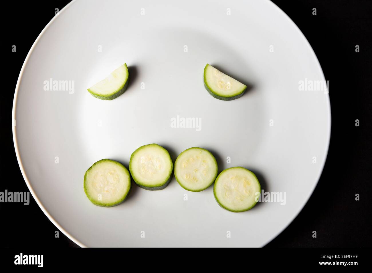 Primo piano di fette di zucchine in un piatto che fa un faccia accigliata Foto Stock