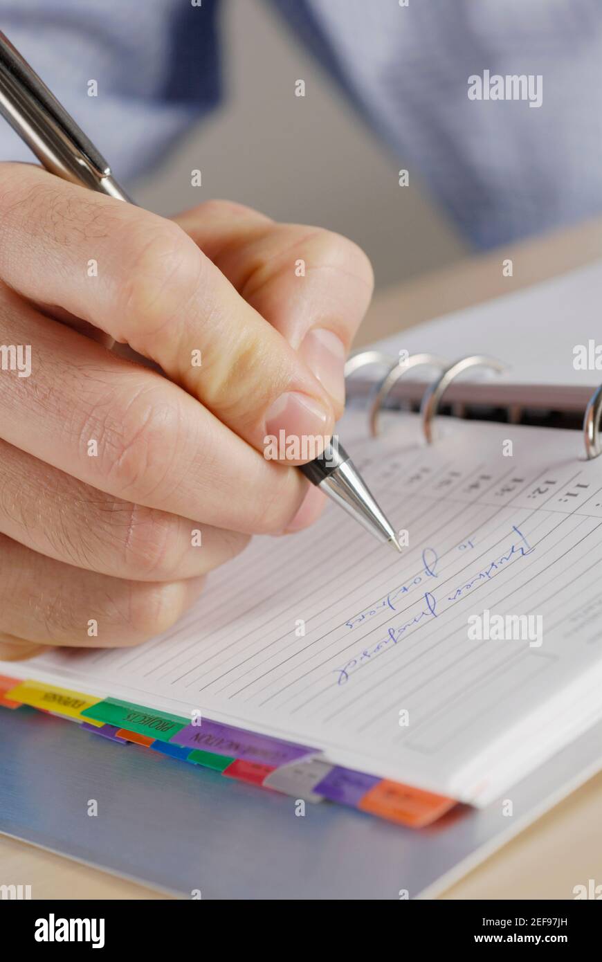 Primo piano di una personÅ½s mano di scrittura su un notebook a spirale Foto Stock