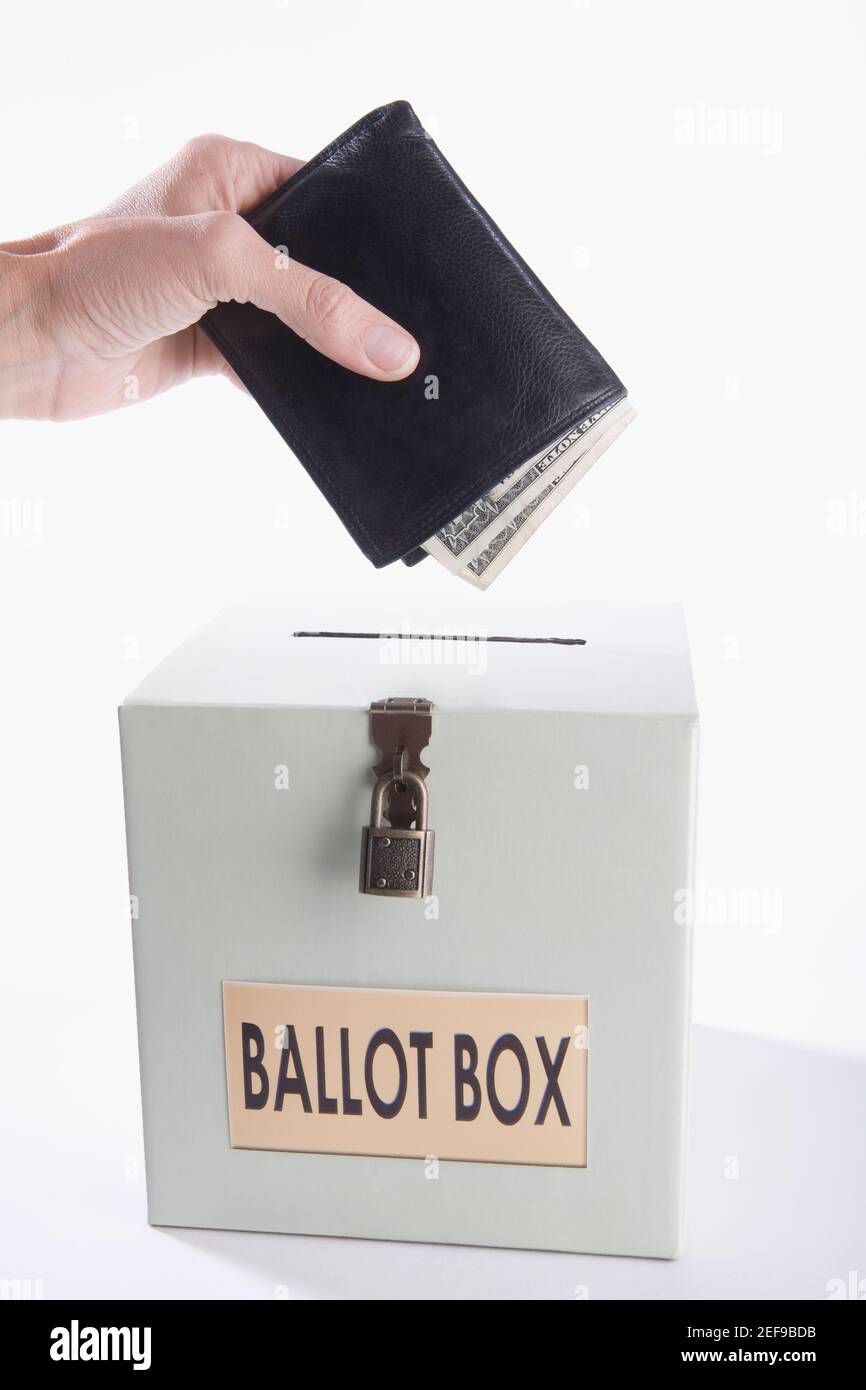 Primo piano di una personÅ½s mano che mette soldi pieni di portafoglio in una scatola di votazione Foto Stock