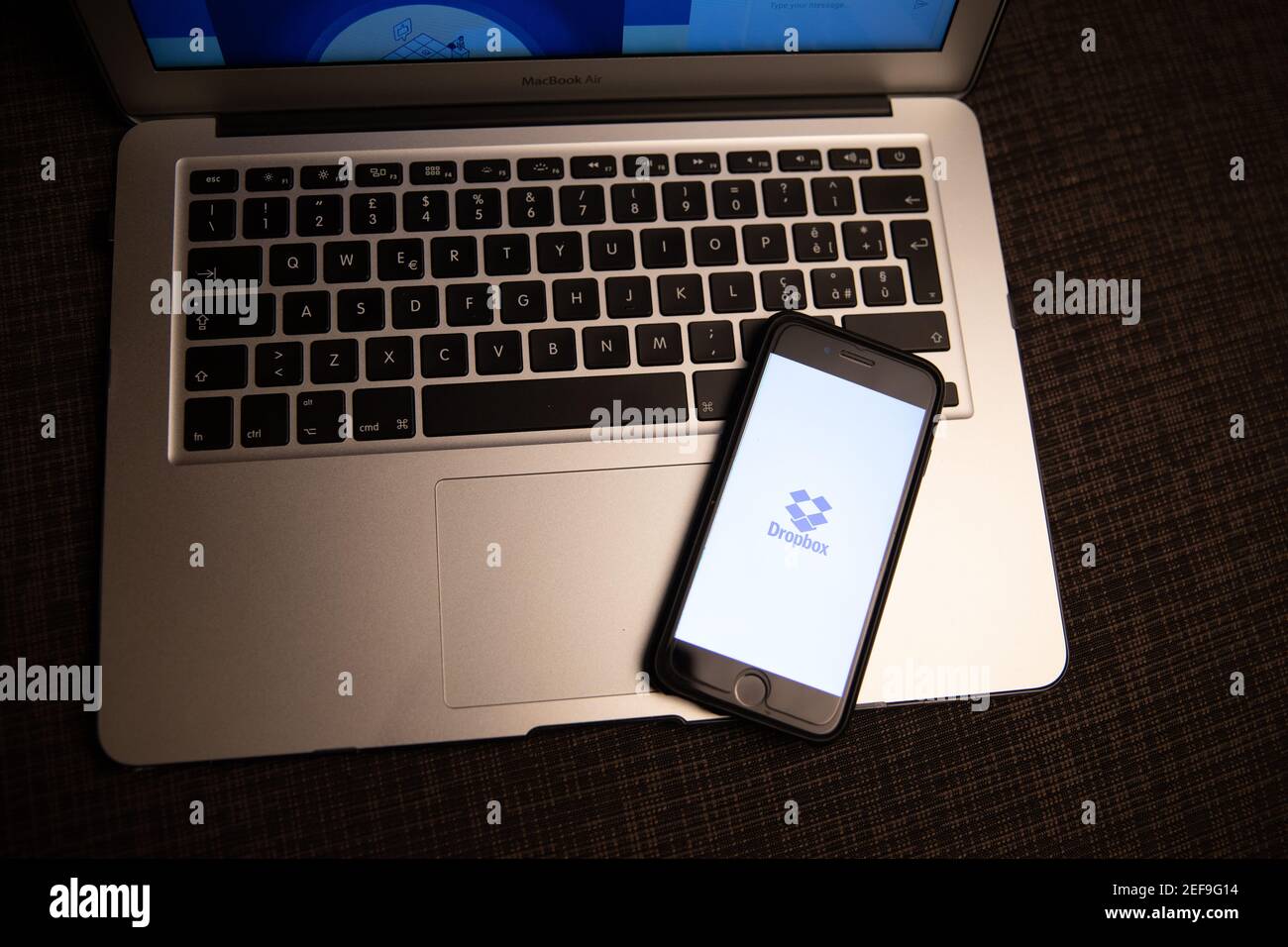 Logo Dropbox sullo schermo di uno smartphone appoggiato su un computer portatile. Dropbox è un servizio di hosting di file che offre servizi cloud e di storage Foto Stock