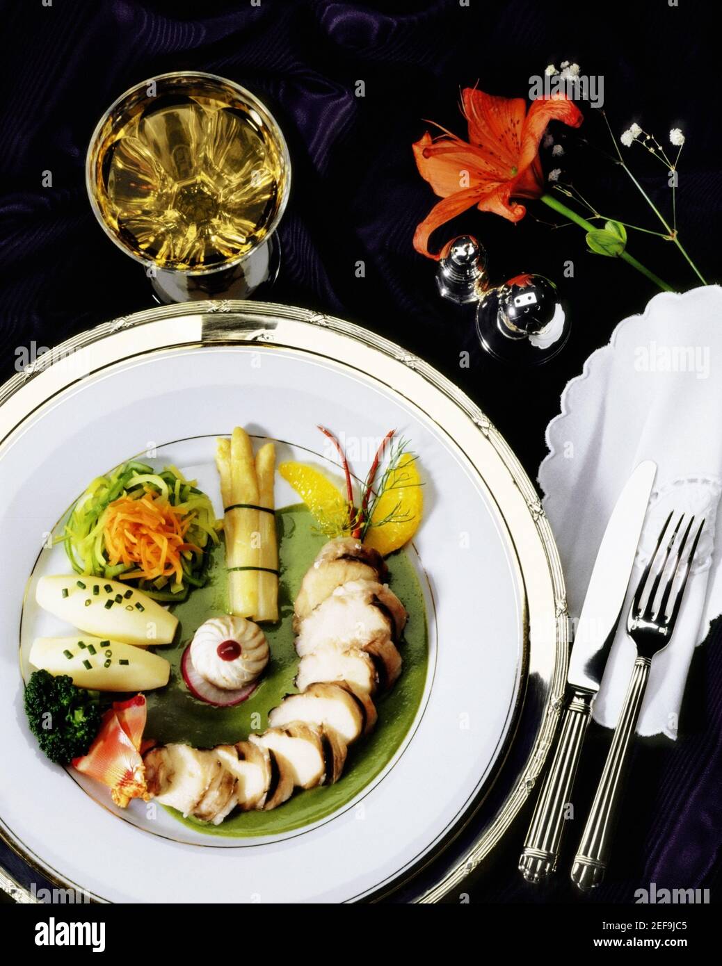 Primo piano di piatto di carne affettata vicino ad un bicchiere di vino bianco Foto Stock