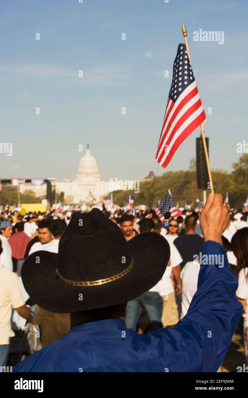 Vista posteriore di una persona che detiene una bandiera americana di fronte a un edificio governativo, California state Capitol Building, USA Foto Stock