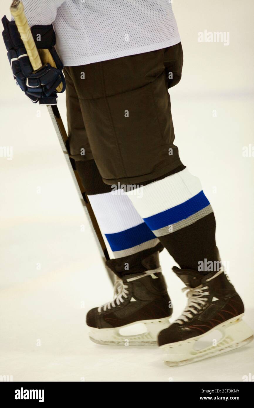 Vista in sezione bassa di un giocatore di hockey su ghiaccio che tiene un bastone per hockey su ghiaccio Foto Stock