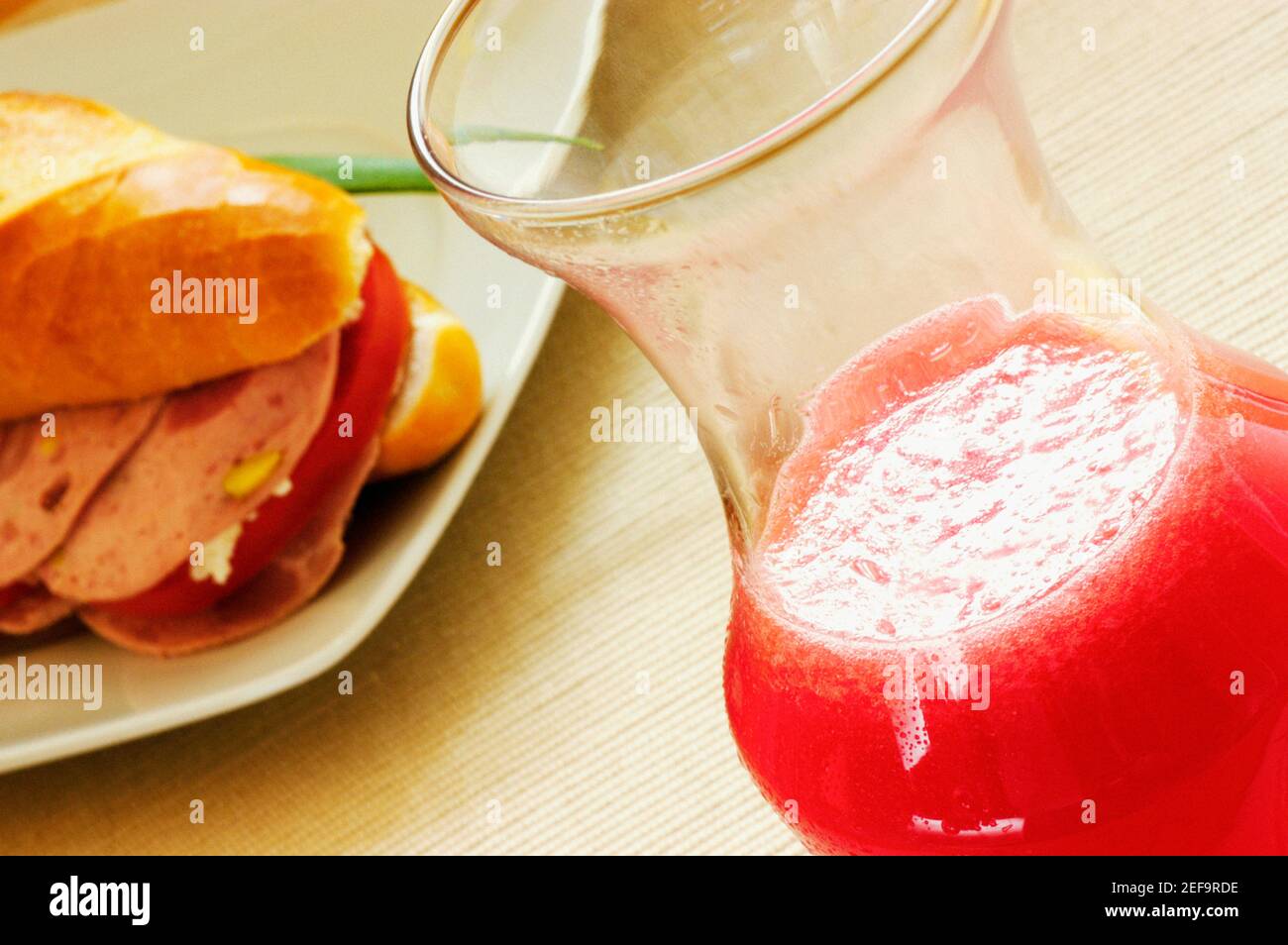 Primo piano di un sandwich su un piatto con un bicchiere di succo Foto Stock