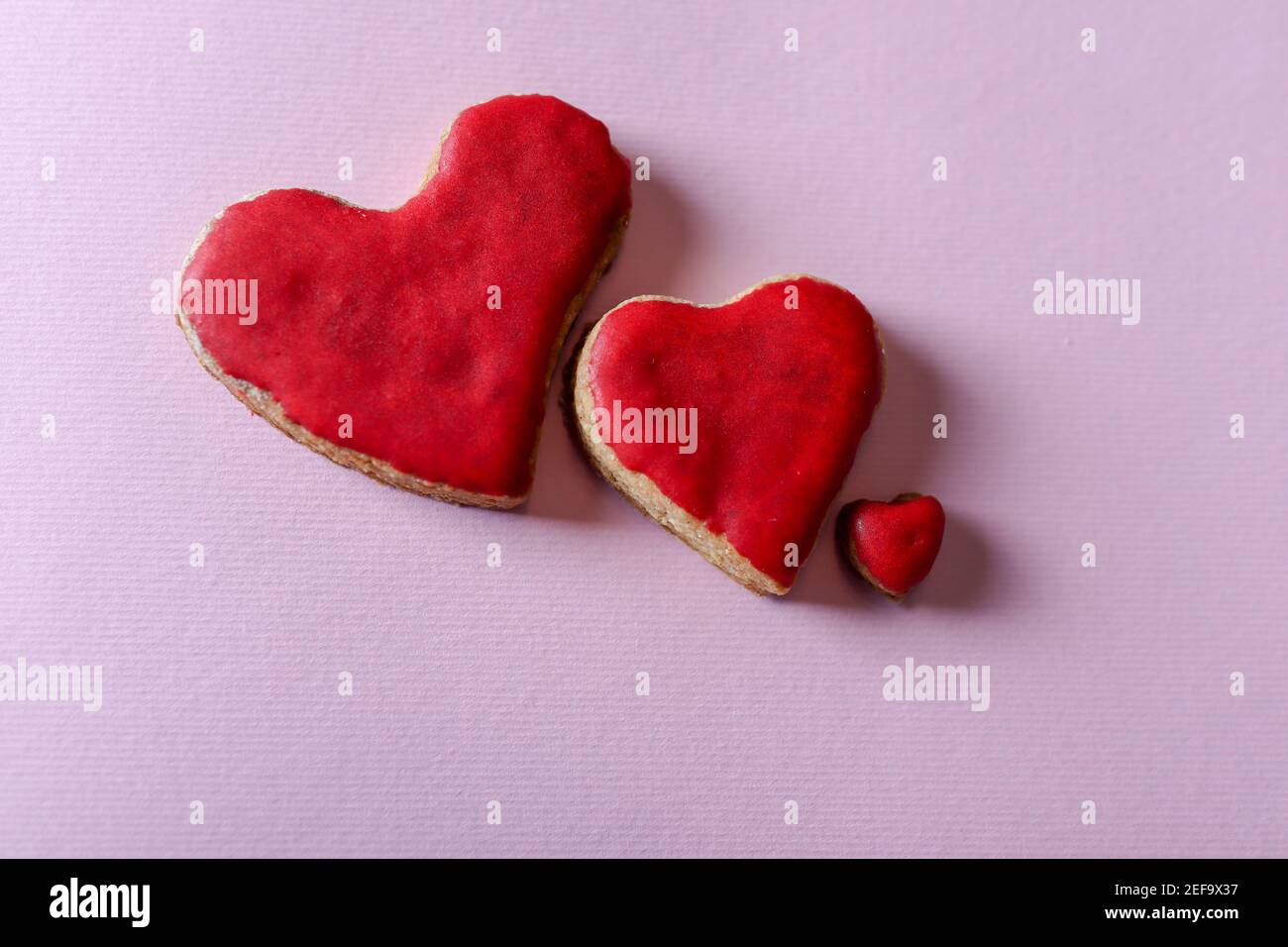 Biscotti rossi fatti in casa cuore isolati su sfondo viola con copia spazio per testo o disegno Foto Stock