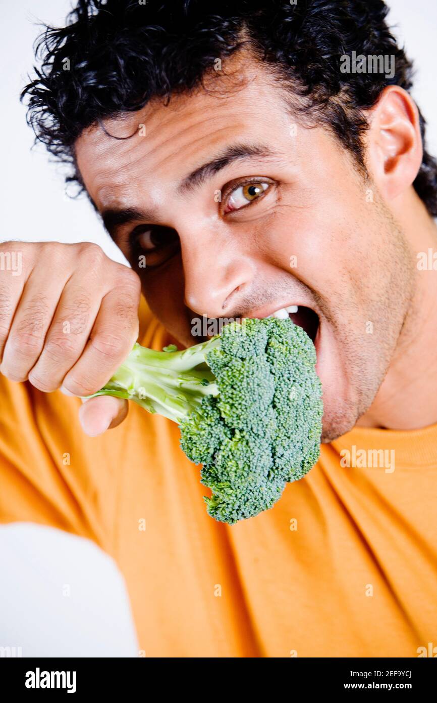 Ritratto di un giovane che mangia un broccoli Foto Stock