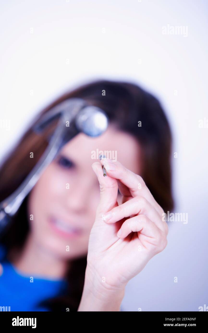 Ritratto di una giovane donna che tiene un martello e un chiodo Foto Stock