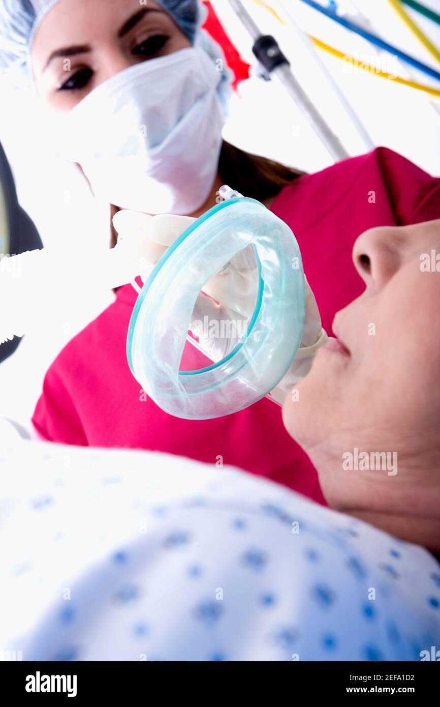 Vista ad angolo basso di una chirurgo femminile che mette un ossigeno maschera su un paziente Foto Stock