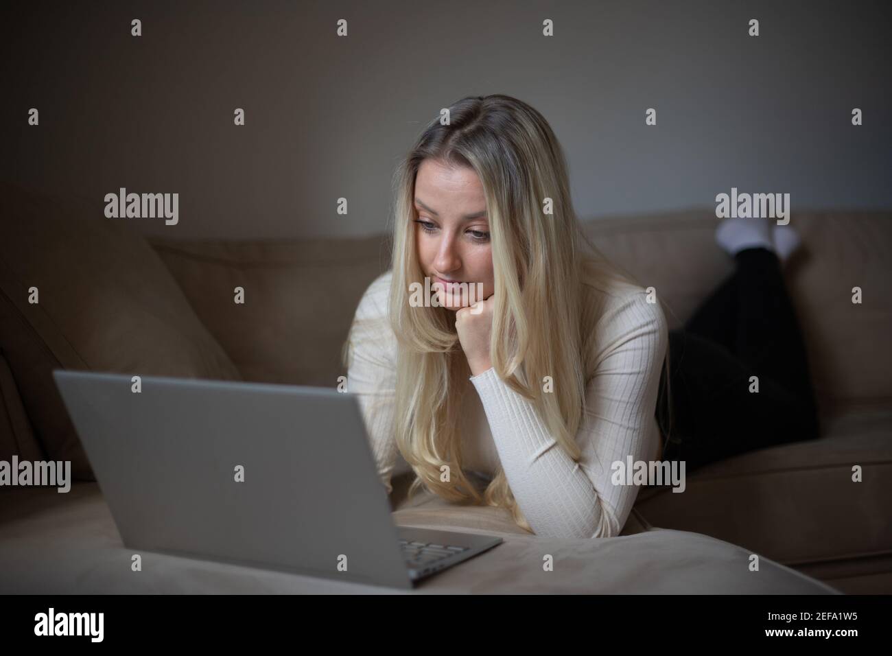 Una ragazza attraente lavora con il suo laptop da casa durante la pandemia del coronavirus Foto Stock