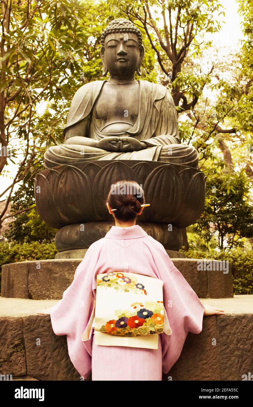 Vista ad angolo basso di una donna matura di fronte Una statua di Buddha Foto Stock