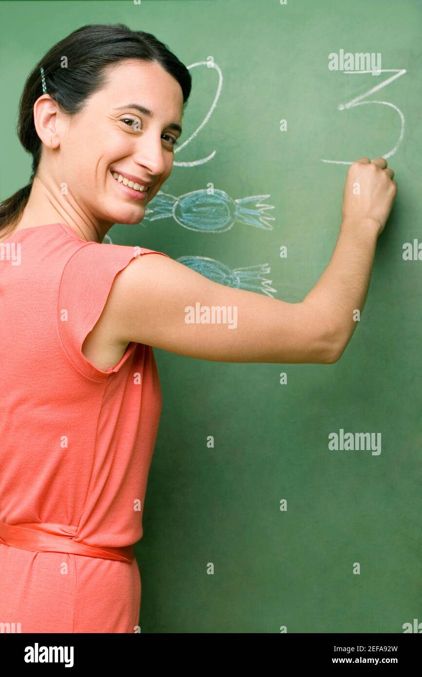 Ritratto di una insegnante di sesso femminile che scrive su una lavagna Foto Stock