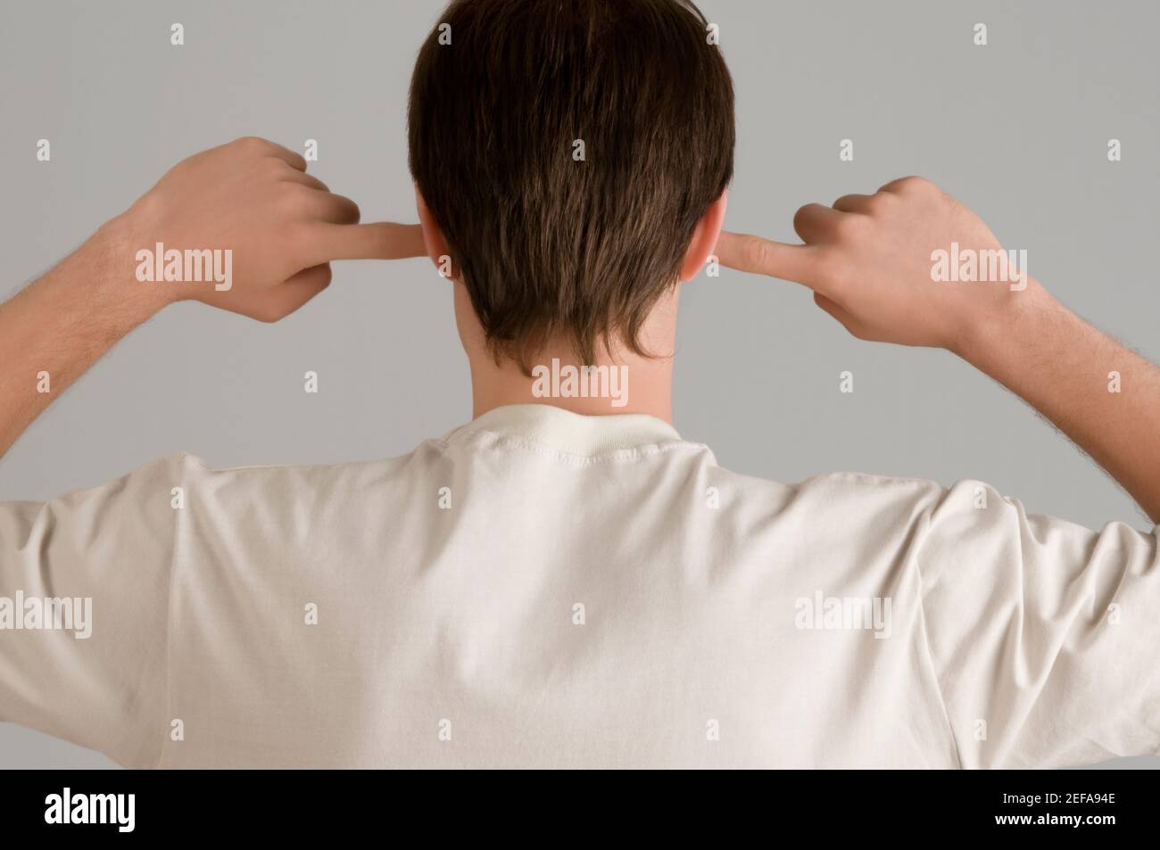 Vista posteriore di un giovane con le dita le orecchie Foto Stock