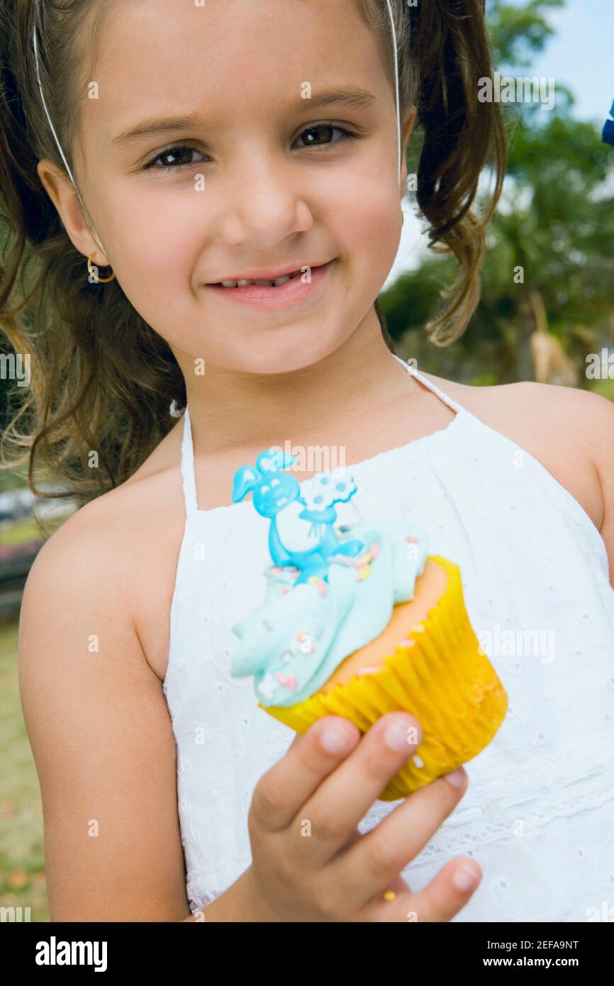 Ritratto di una ragazza che tiene una cupcake e sorride Foto Stock