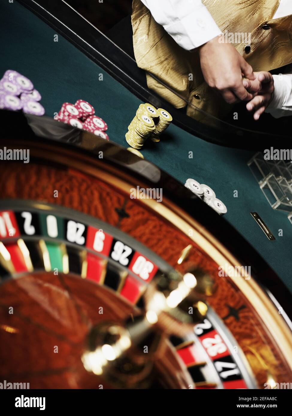 Vista in sezione intermedia di un operaio del casinò in piedi ad a. tavolo roulette Foto Stock