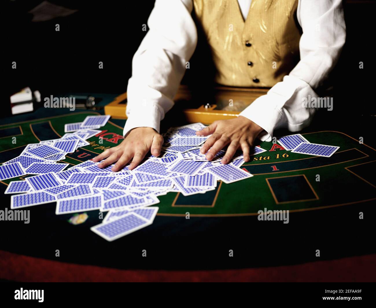 Vista in sezione intermedia di un operaio di casinò che mischiava le carte da gioco su un tavolo da gioco Foto Stock