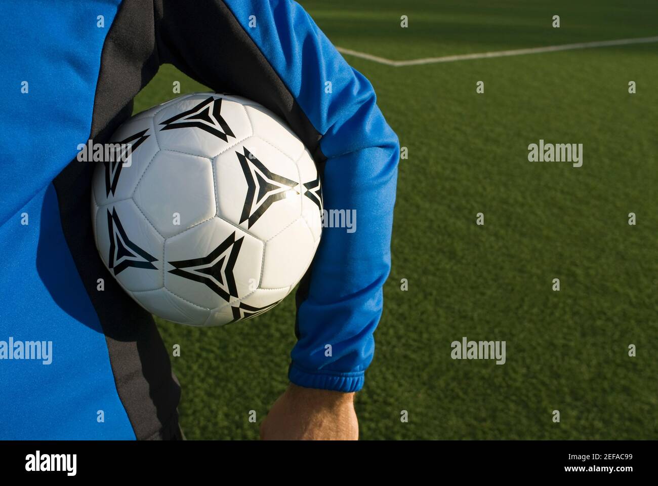 Vista in sezione centrale di un uomo che tiene una palla da calcio sotto il braccio Foto Stock