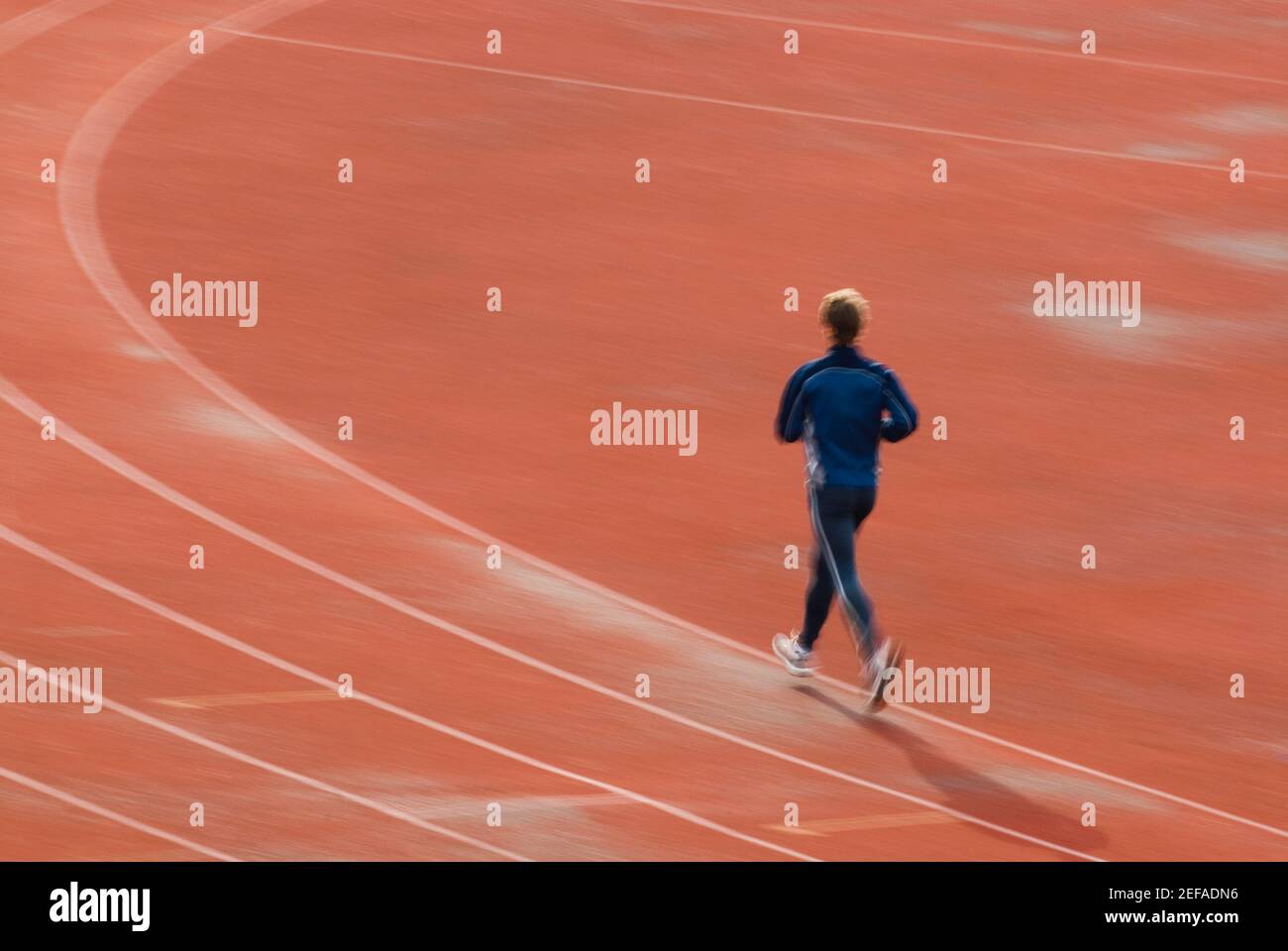 Vista posteriore di un uomo che corre su una pista sportiva Foto Stock