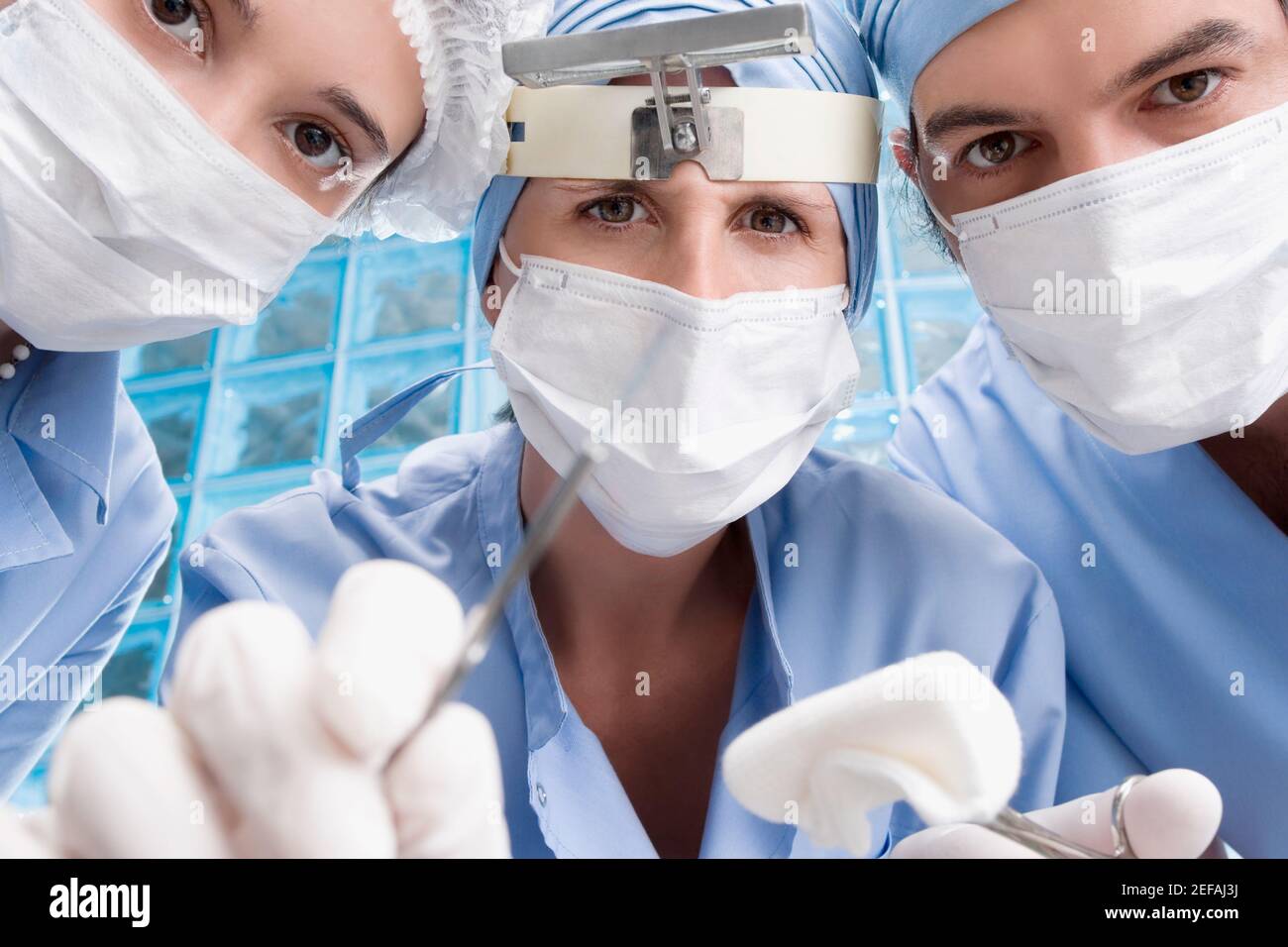 Primo piano di due chirurghi femminili e di un chirurgo maschile una sala operatoria Foto Stock