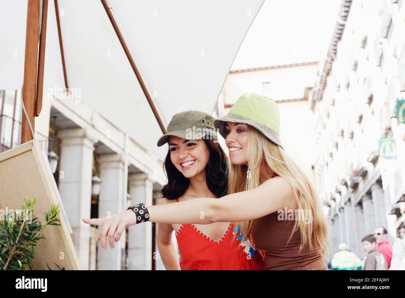 Giovane donna e una donna mid adulta che guarda a. dipingere in un caffè sul marciapiede Foto Stock