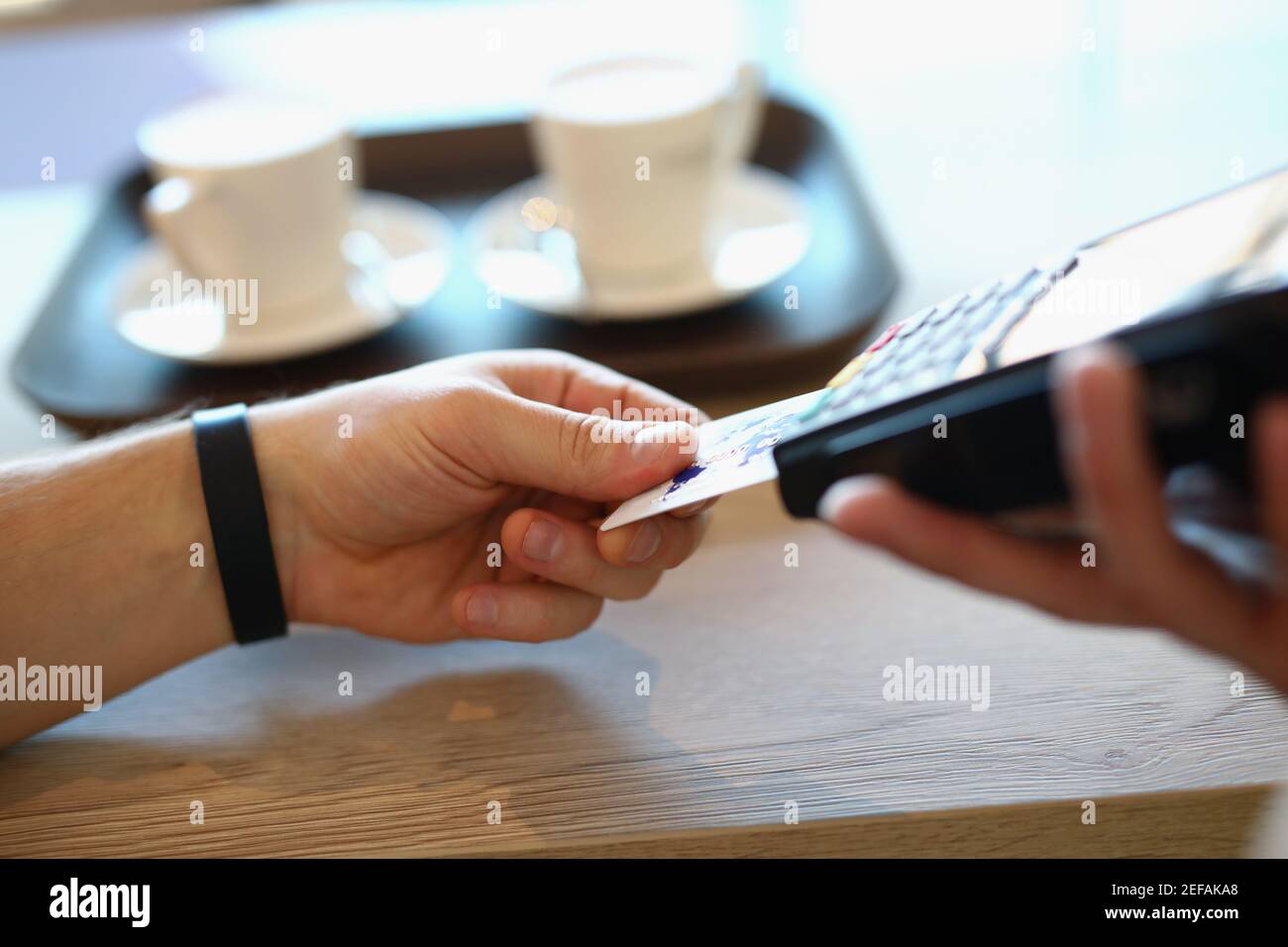 La mano maschile inserisce la carta di credito in plastica nel terminale di pagamento Foto Stock