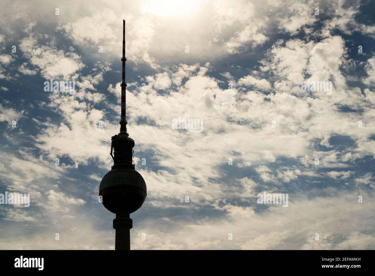 La torre della televisione di Berlino è retroilluminata come una silhouette contro a. cielo blu con nuvole bianche Foto Stock