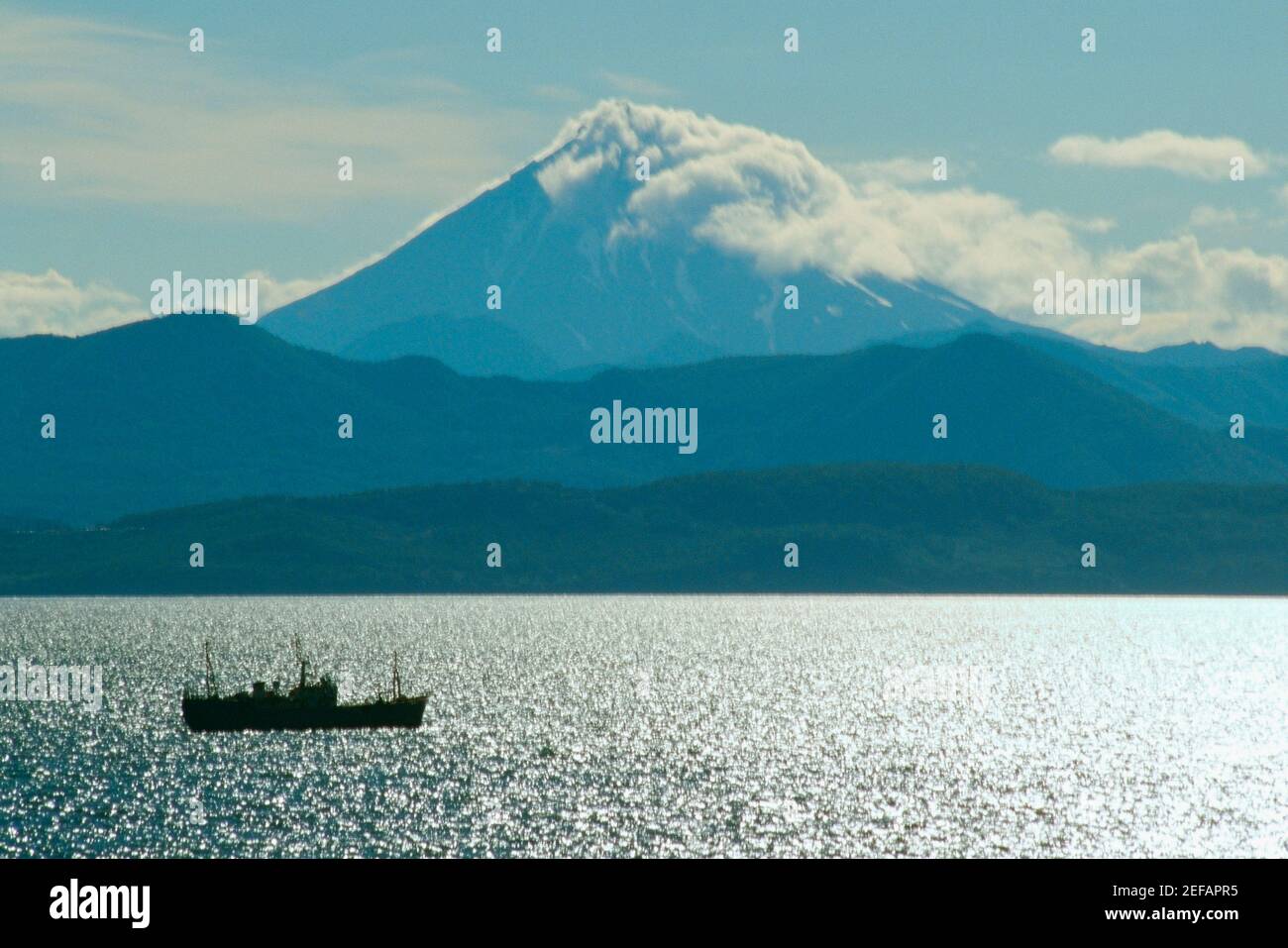 Barca nel fiume con un vulcano sullo sfondo, Vulcano Viluchinsky, Baia di Petropavlovsk, Kamchatka, Russia Foto Stock