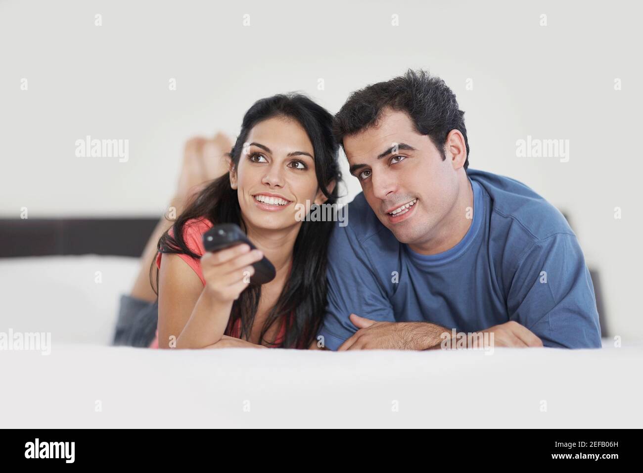 Giovane donna che aziona un telecomando con un mid adult uomo accanto a lei Foto Stock