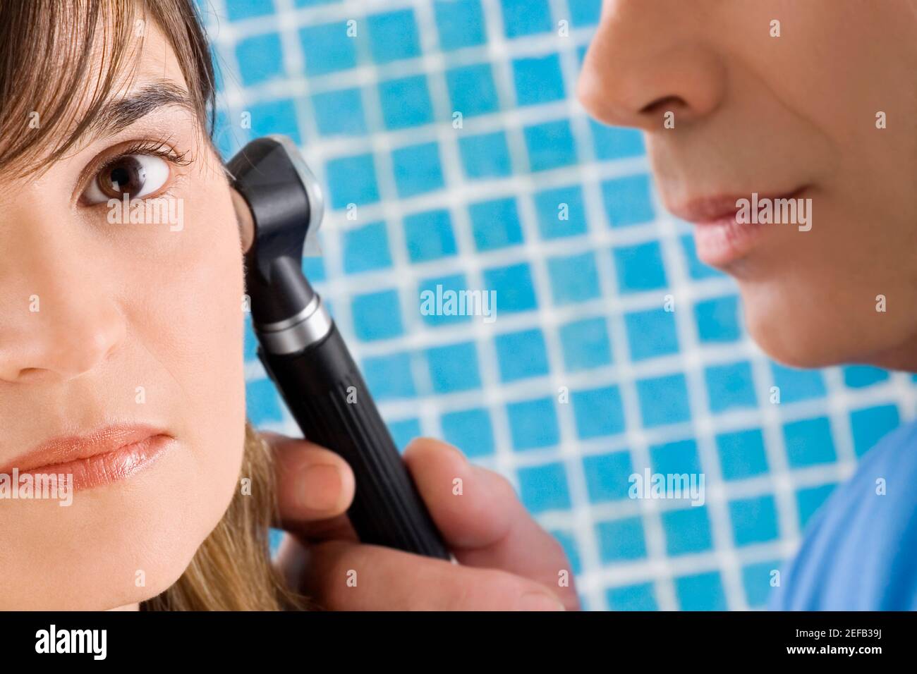 Primo piano di un medico maschile che esamina un orecchio womanÅ½s maturo Foto Stock