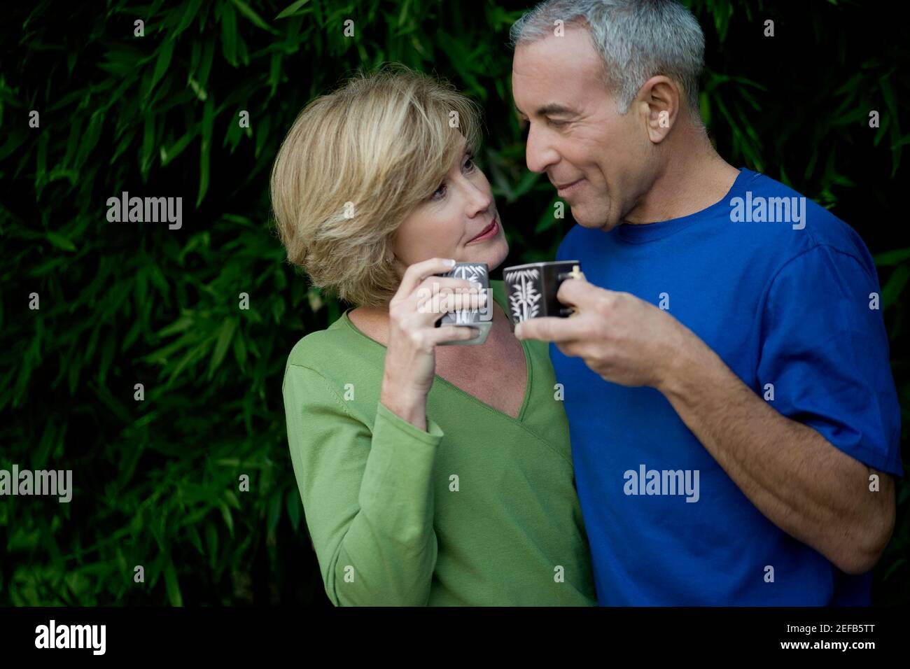 Primo piano di un uomo anziano con una donna matura che tiene tazze da tè e guardarsi l'un l'altro Foto Stock