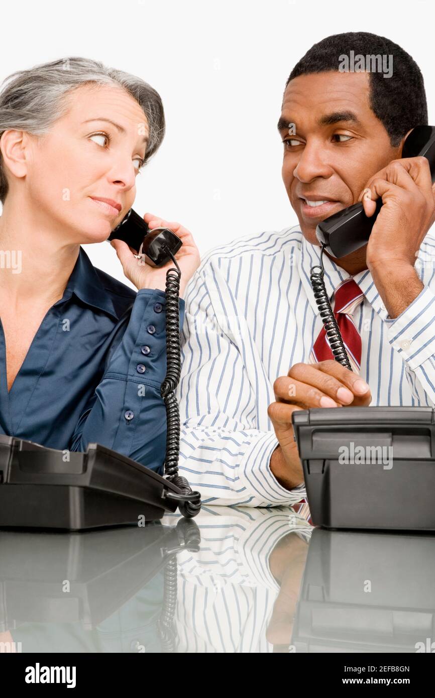 Uomo d'affari e una donna d'affari che parla su telefoni fissi Foto Stock
