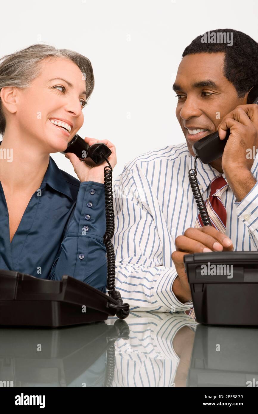 Uomo d'affari e una donna d'affari che parla su telefoni fissi Foto Stock