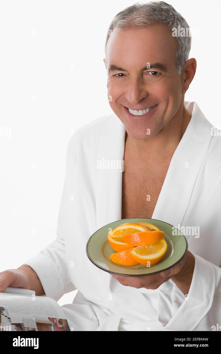 Ritratto di un uomo anziano che tiene un piatto di arancio e sorridendo Foto Stock