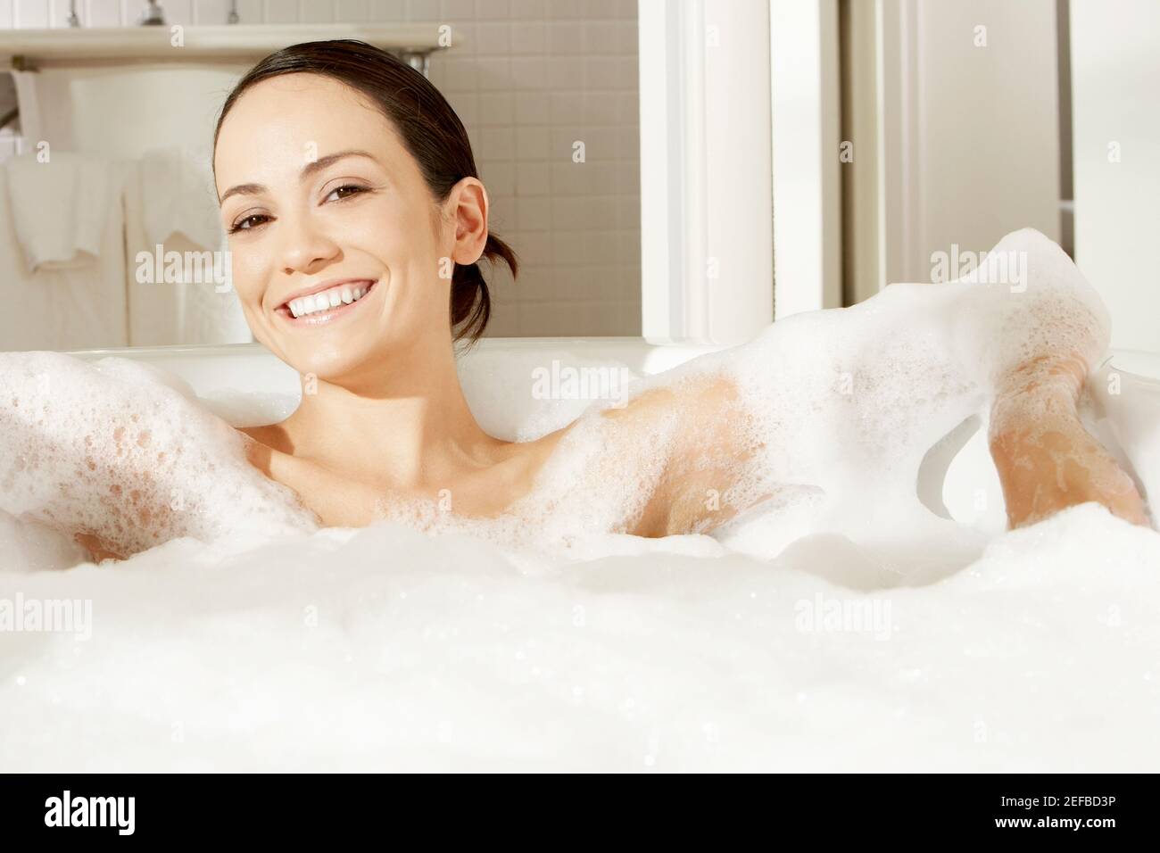 Ritratto di una giovane donna reclinata in un bagno di bolla Foto Stock
