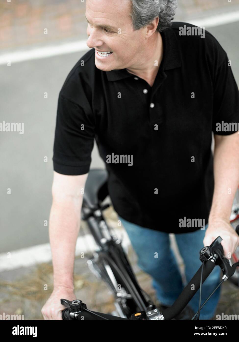 Vista ad alto angolo di un uomo maturo in piedi con un bicicletta e sorridente Foto Stock