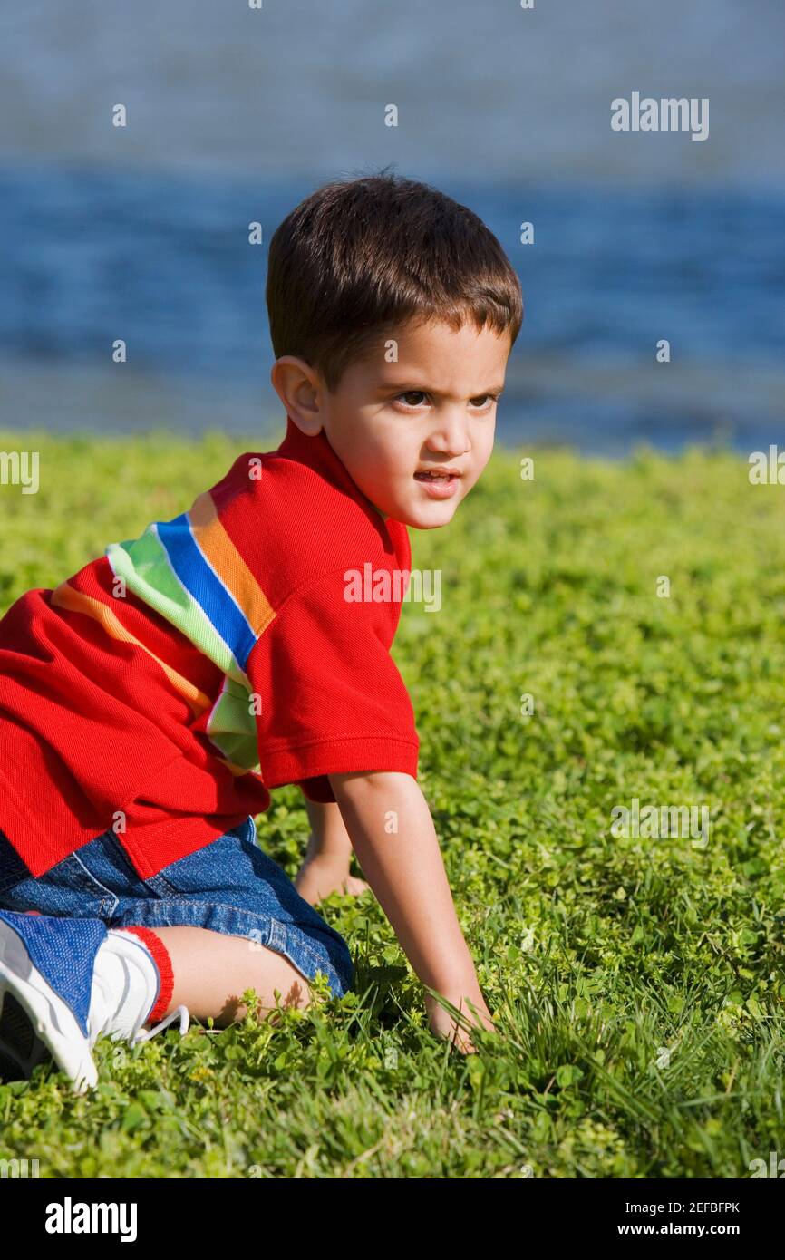 Profilo laterale di un ragazzo inginocchiato su un prato Foto Stock