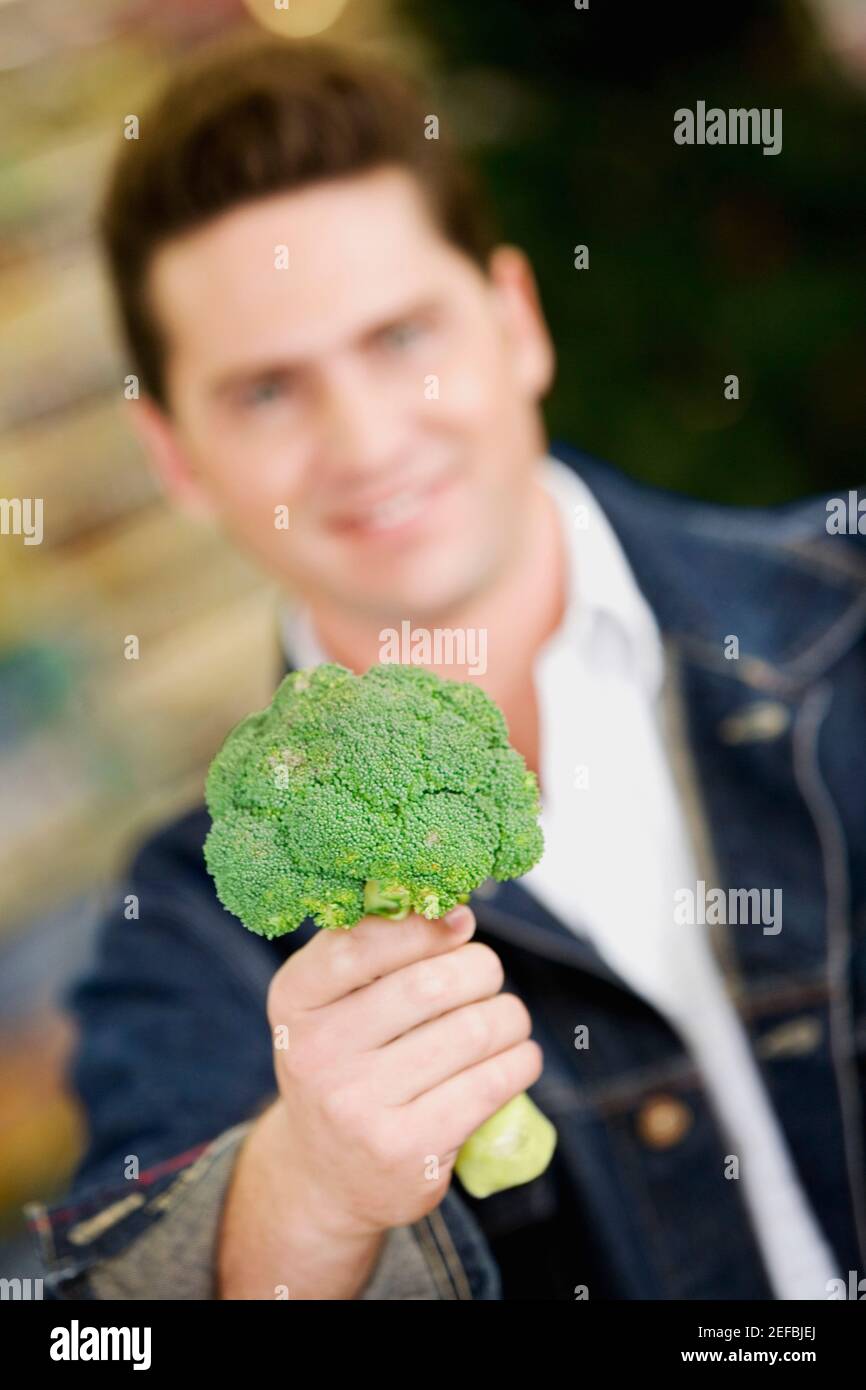 Ritratto di un giovane che tiene broccoli Foto Stock
