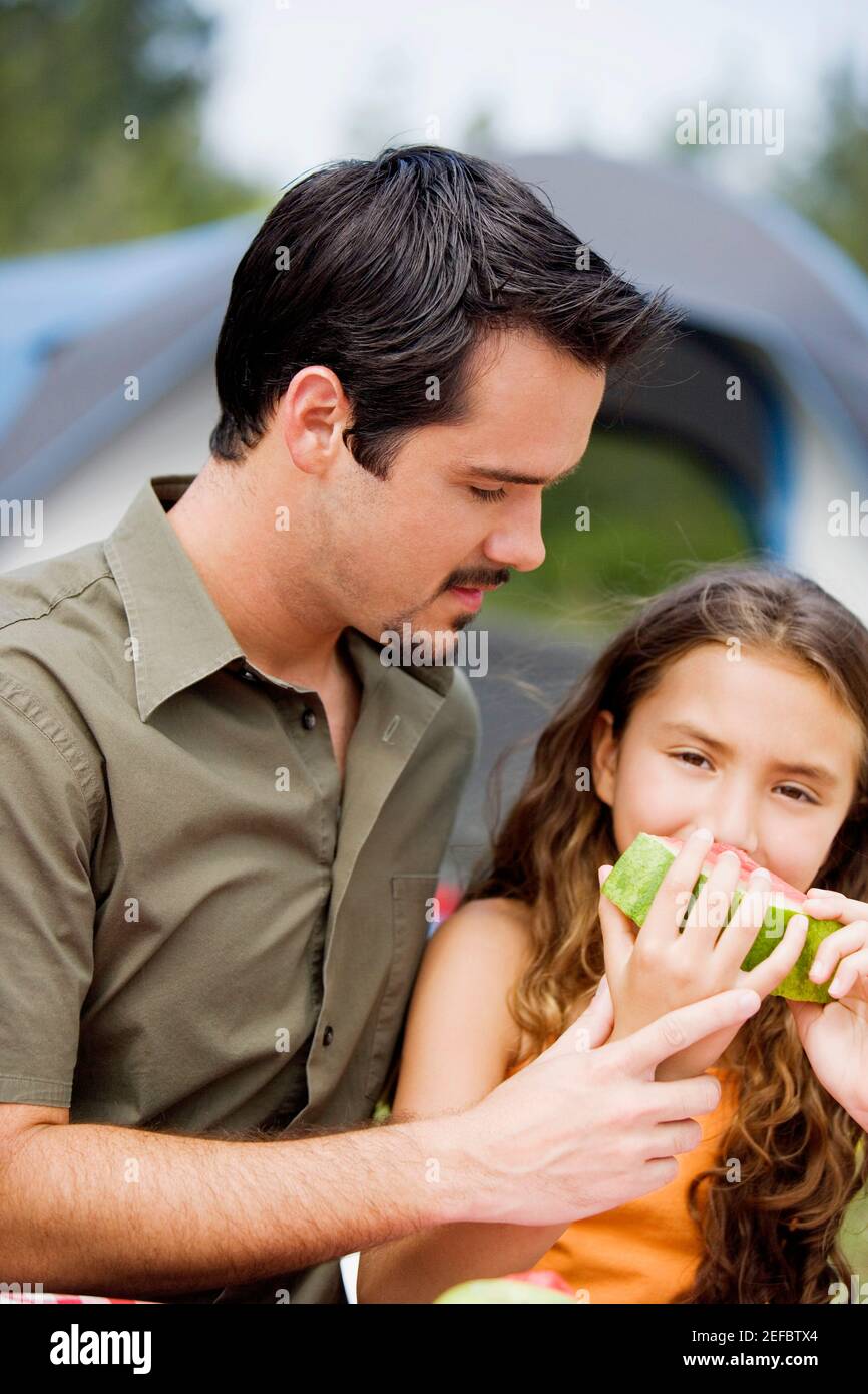 Primo piano di un padre e di sua figlia che mangiano una fetta di anguria Foto Stock