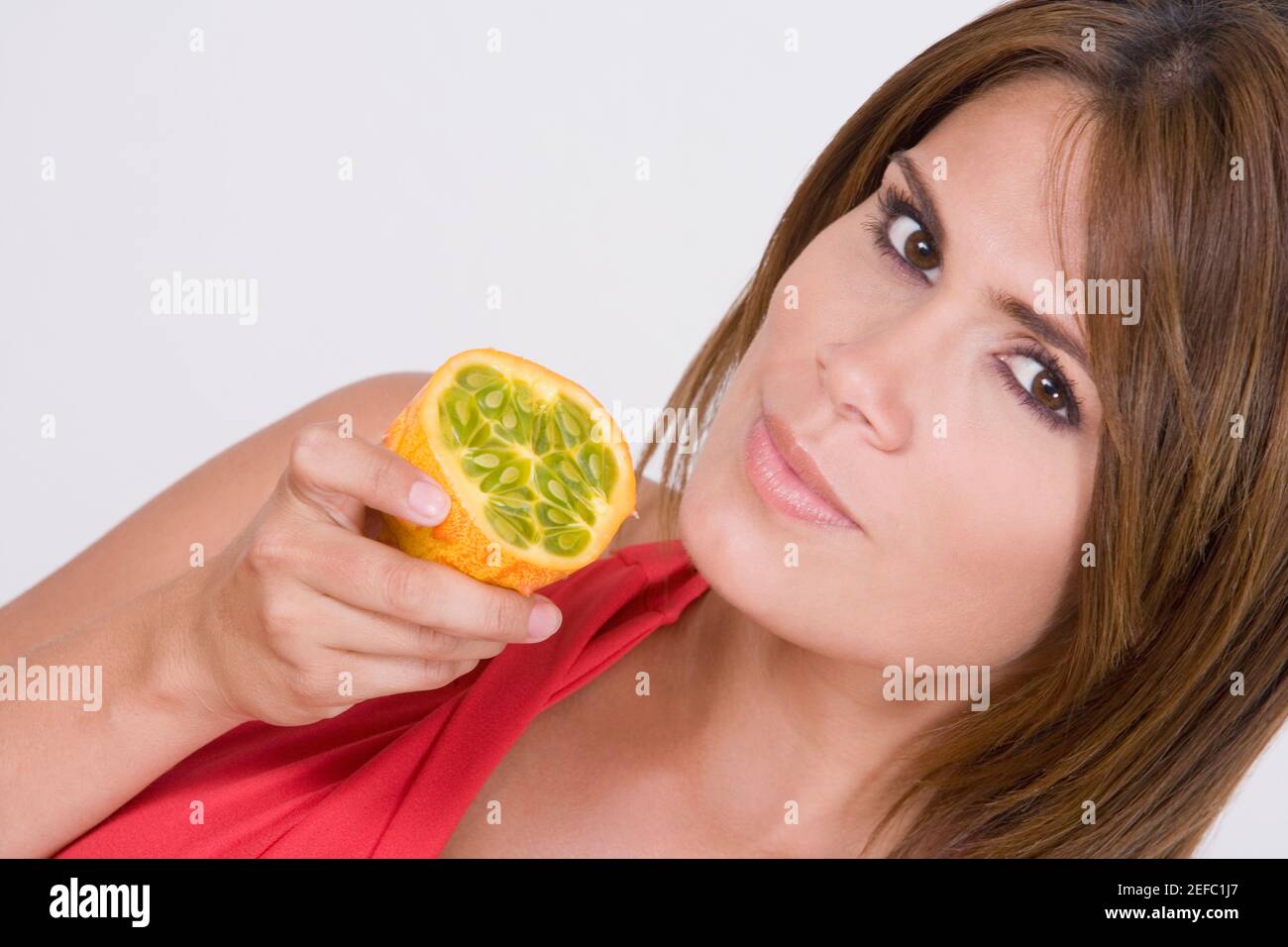 Ritratto di una giovane donna che tiene un mezzo frutto kawani Foto Stock