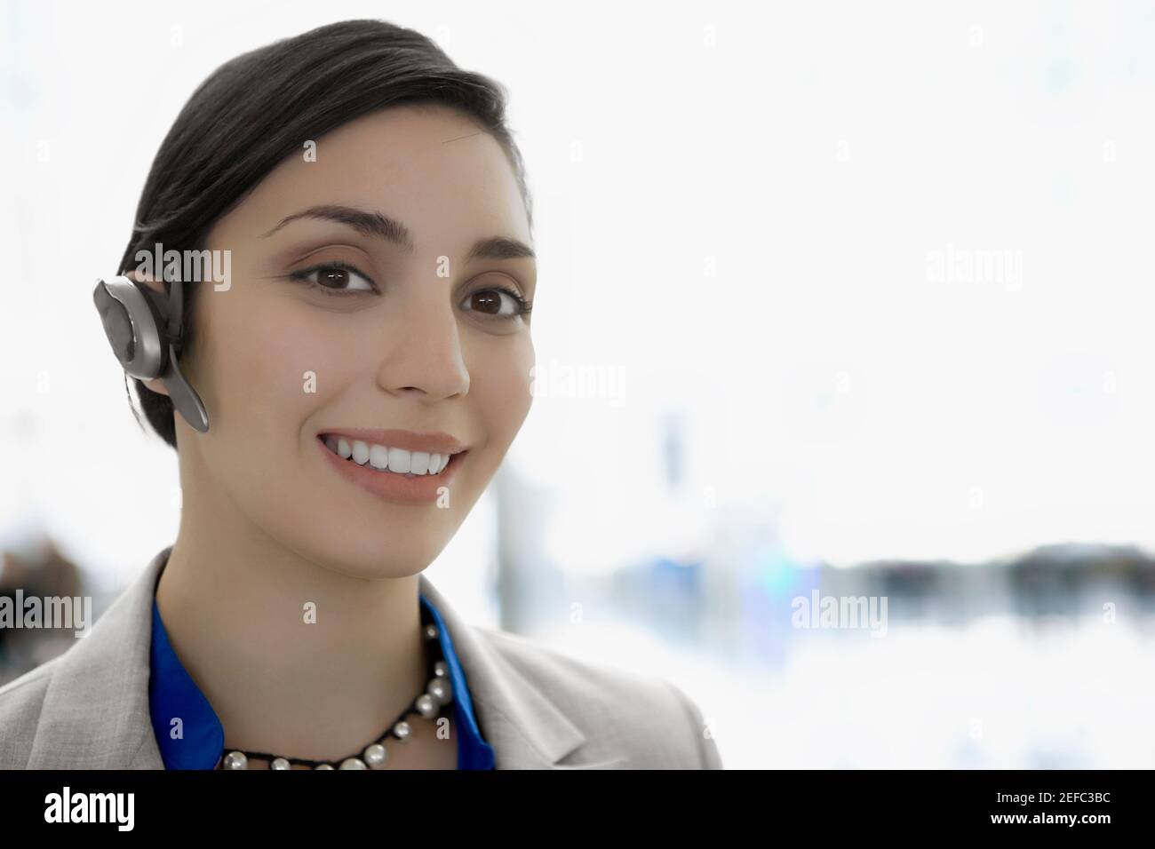 Ritratto di una donna d'affari che indossa un dispositivo a mani libere e. sorridente Foto Stock