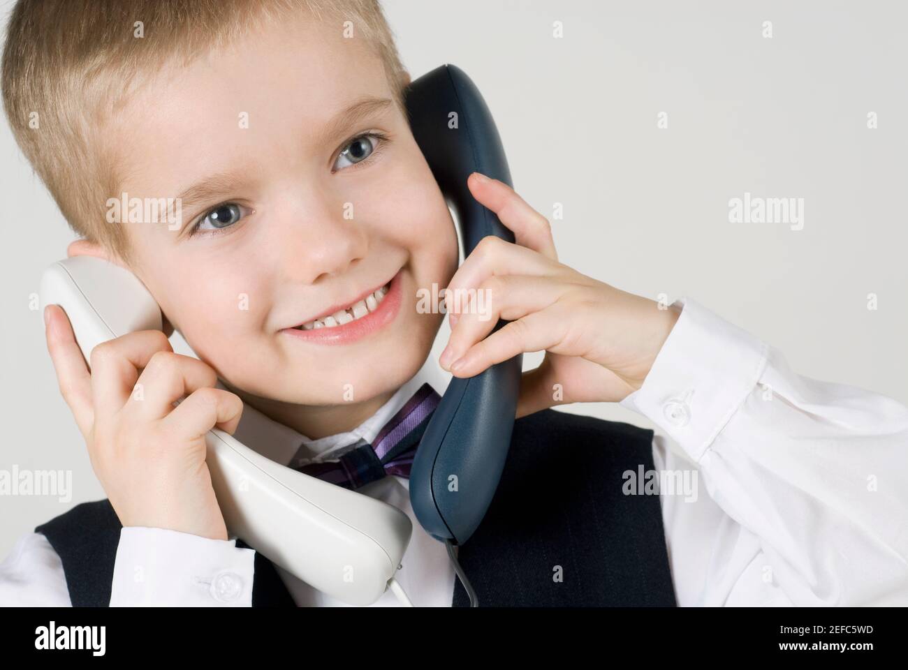 Primo piano di un ragazzo che parla su due telefoni fissi Foto Stock