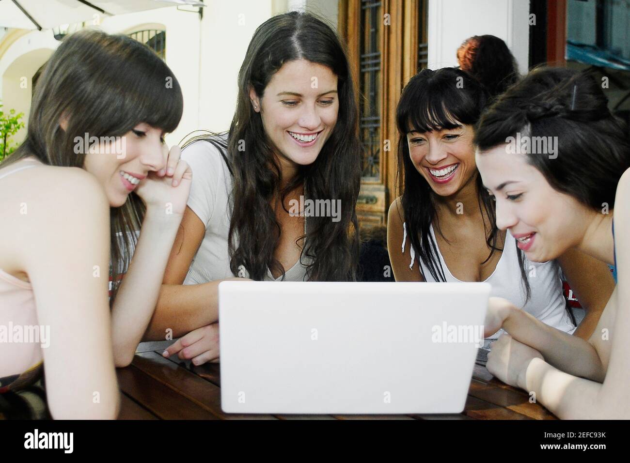 Due donne mid adulte e due giovani donne sorridenti utilizzando un computer portatile Foto Stock