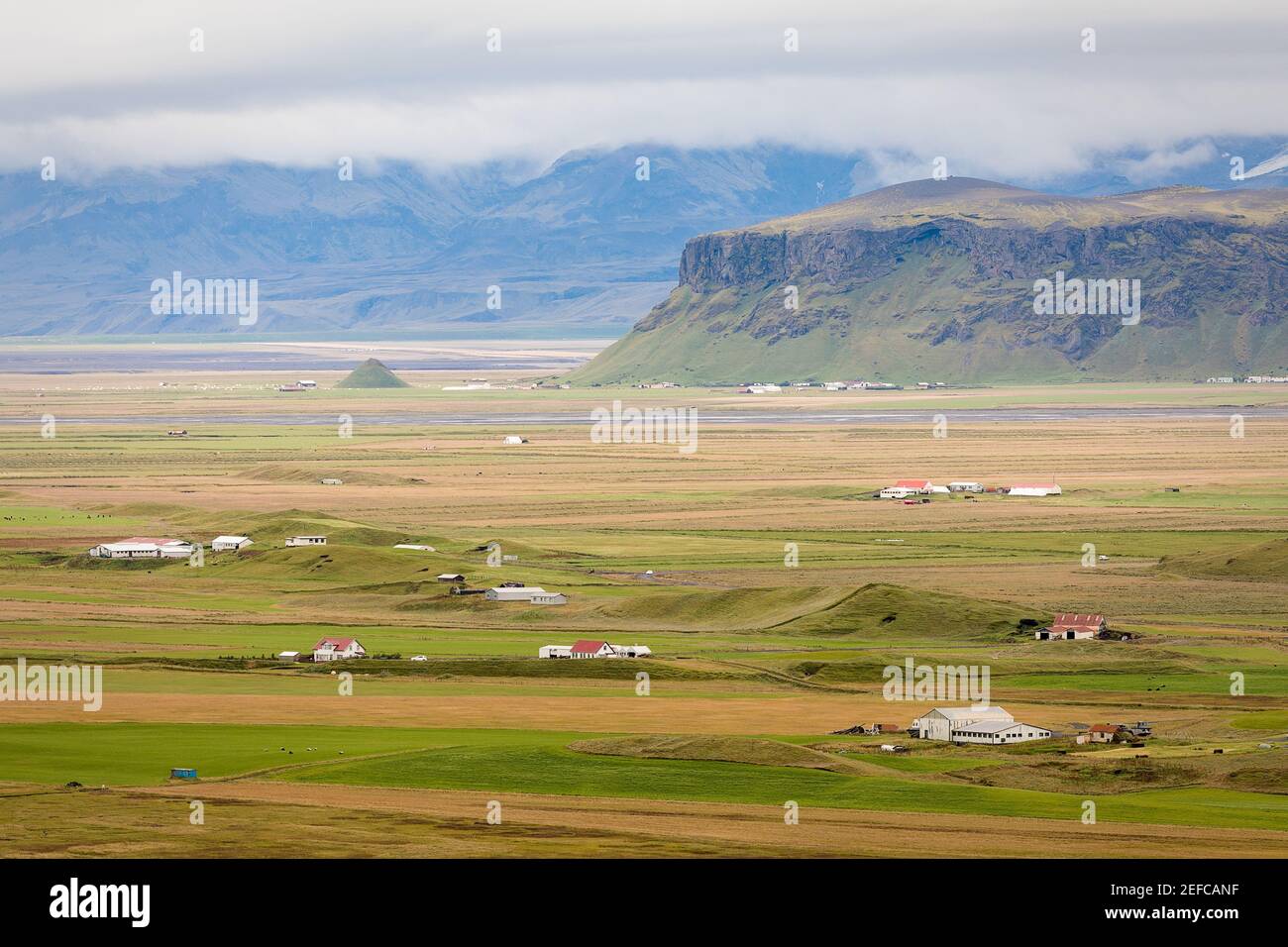 Vista sulla campagna islandese con le sue fattorie ai piedi delle montagne. Foto Stock