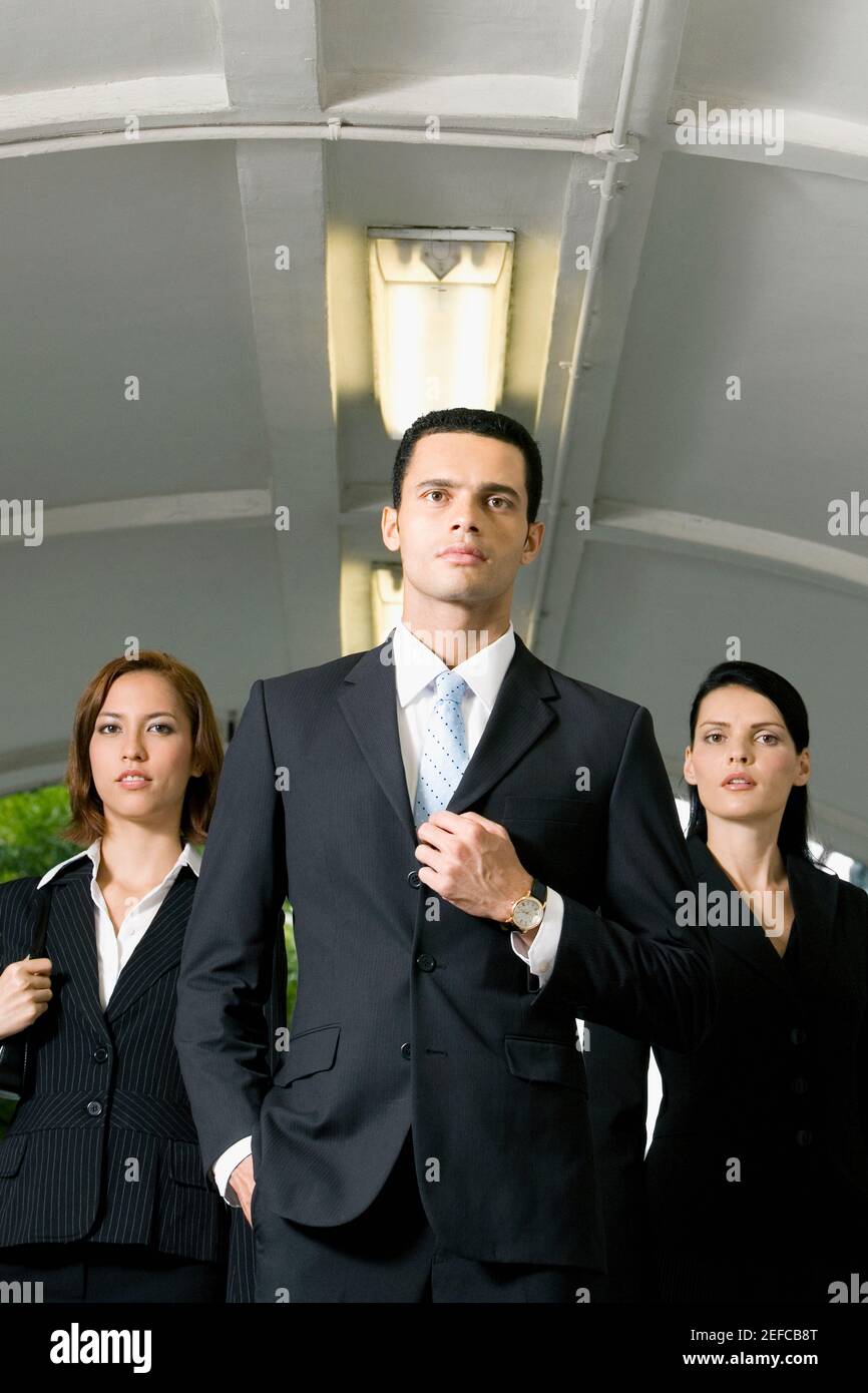 Uomo d'affari in piedi con due donne d'affari in una metropolitana Foto Stock